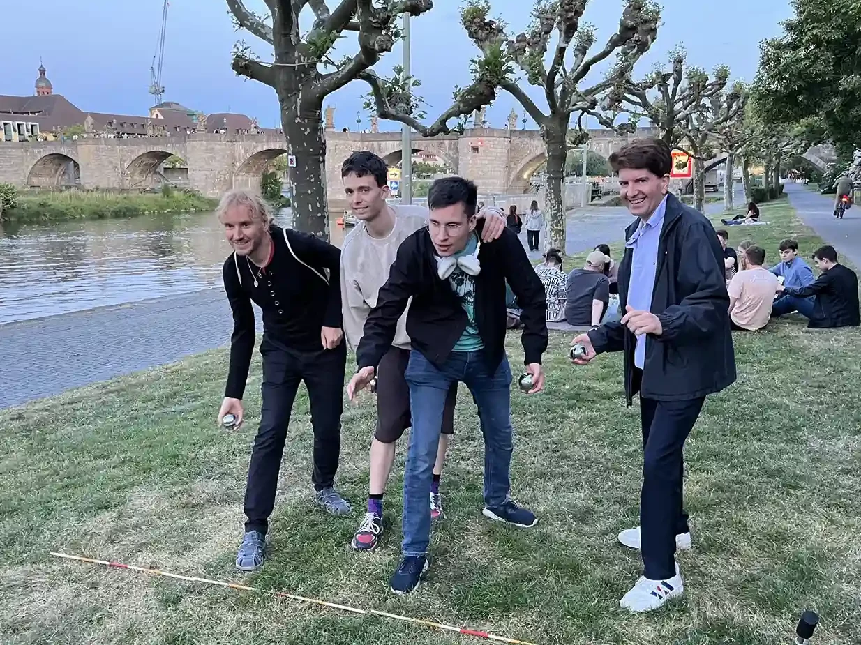 Mehrere Personen spielen gemeinsam Boule am Mainufer in Würzburg bei einem Treffen des WuF-Zentrums.